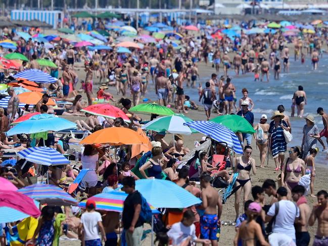 (FILES) People crowd the beach in Valencia on July 5, 2024. A record 94 million foreign tourists craving for sun, sand and culture flocked to Spain in 2024 as the sector drives the country's bullish economy, the tourism minister said on January 15, 2025. "In 2024, the forecast for international tourists is around 94 million, 10 percent more than 2023. Spain therefore continues to break records," Industry and Tourism Minister Jordi Hereu said in Madrid. (Photo by Jose Jordan / AFP)