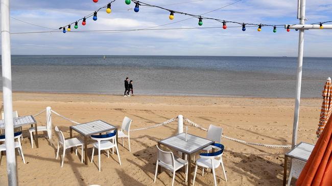 People walk past a closed cafe on Melbourne's St Kilda Beach on Tuesday. Picture: AFP