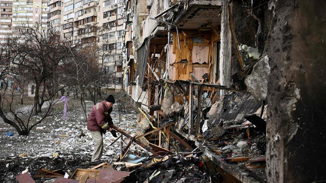 A man clears debris at a damaged residential building at Koshytsa Street, a suburb of the Ukrainian capital Kyiv, where a military shell allegedly hit. Picture: Daniel Leal / AFP)