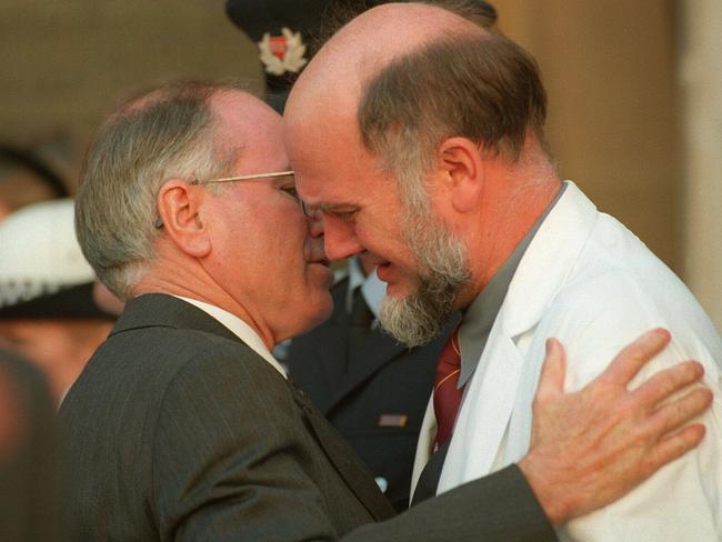John Howard comforts the Royal Hobart Hospital's emergency department specialist Brian Warpole following memorial service at St David's cathedral in Hobart in 1996.