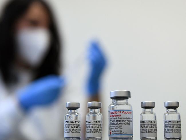 Vials of the COVID-19 vaccine by Moderna (C) and Pfizer / BioNTech against the novel coronavirus stand on a table in a vaccination center in Sonthofen, southern Germany, on November 30, 2021, amid the ongoing coronavirus Covid-19 pandemic. (Photo by Christof STACHE / AFP)