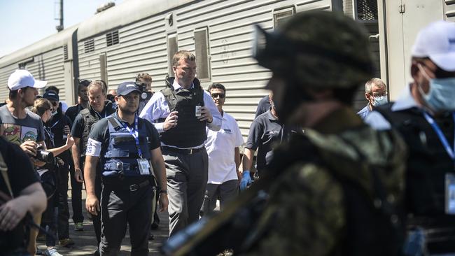 Monitors on the ground ... from the Organisation for Security and Cooperation in Europe (OSCE) and members of a forensic team inspect a refrigerator wagon containing the remains of victims from the downed Malaysia Airlines Flight MH17. Picture: Bulent Kilic