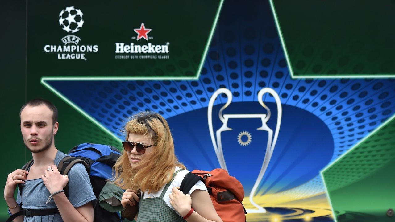 Tourists walk past alarge sign showcasing the logo for the 2018 UEFA Champions League Final in the Ukrainian capital of Kiev