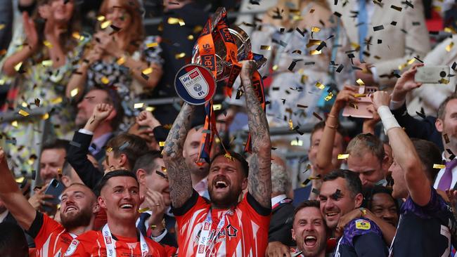 Sonny Bradley lifts the trophy as Luton's players celebrate. (Photo by Adrian DENNIS / AFP)