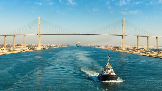 Ship's convoy with cargo vessel container ship passing through Suez Canal, in the background - the Suez Canal Bridge, also known as Al Salam Bridge, Suez Canal, Egypt