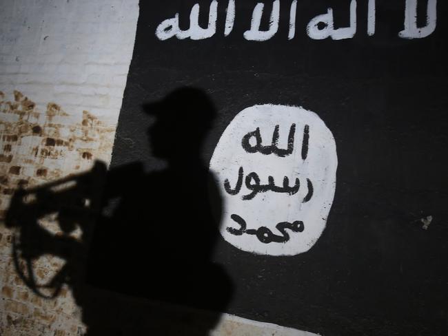 A member of the Iraqi forces walks past a mural bearing the logo of the Islamic State group on the southern outskirts of Mosul. Picture: AFP