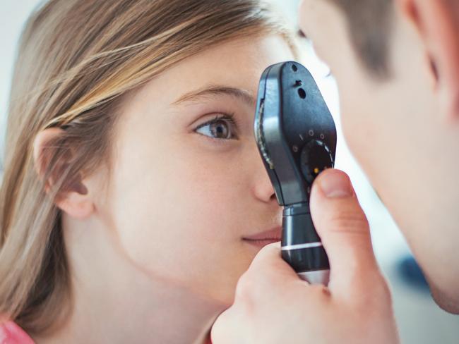 Closeup side view of early 40's unrecognizable optician examining eyesight of his little female patient with a phoropter device. The girls is aged 9, with brown eyes and hair. Picture: Istock