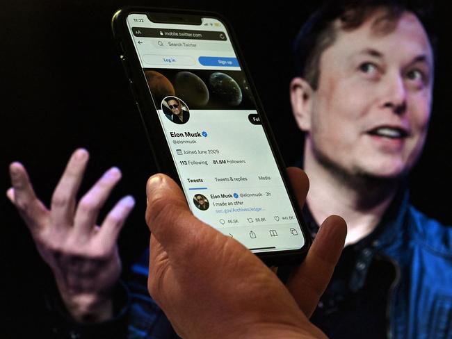 (FILES) In this file photo taken on April 14, 2022 a phone screen displays the Twitter account of Elon Musk with a photo of him shown in the background, in Washington, DC. - Twitter suspended December 15, 2022, the accounts of more than a half-dozen journalists who had been writing about the company and its new owner Elon Musk. Some of the journalists had been tweeting about Twitter shutting down an @ElonJet account that tracked flights of the billionaire's private jet and about versions of that account hosted at other social networks. (Photo by Olivier DOULIERY / AFP)