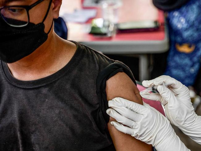 A health worker injects a man with a shot of the Inavac vaccine for Covid-19 at the Jakarta provincial health office on December 19, 2023, during a vaccination campaign held to administer a fifth precautionary vaccine dose amid concerns that Covid-19 cases could spike during the Christmas and New Year holidays. (Photo by BAY ISMOYO / AFP)