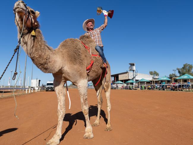 Melbourne jockey Glen Boss rides Billy the Camel and holds the Melbourne Cup high at Boulia Camel Races as the famous trophy starts its tour of Australia. Picture: Jay Town