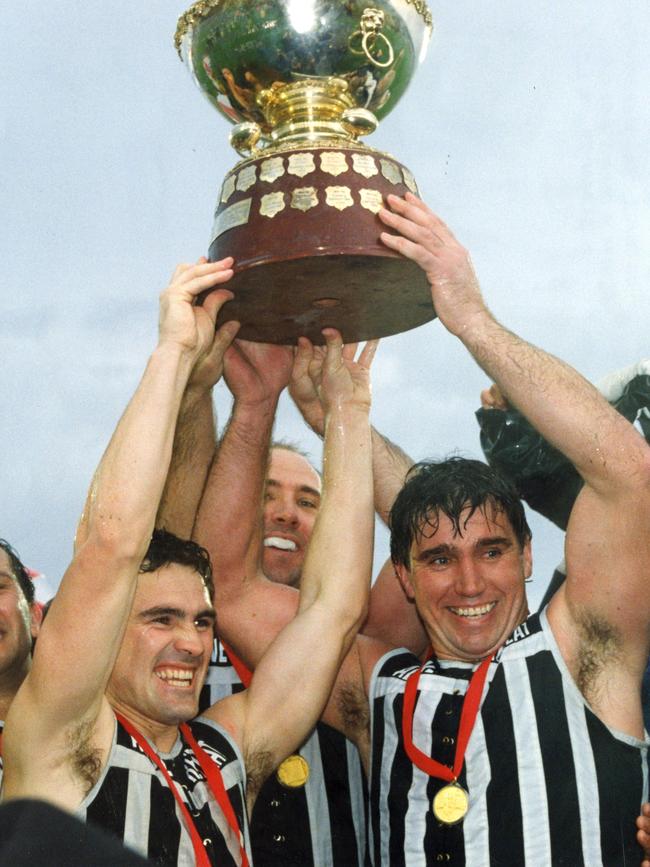 Port Adelaide captain Greg Phillips, right, and vice-captain Tim Ginever, left, hoist aloft the Thomas Seymour Hill premiership cup after their win against Glenelg in the 1992 SANFL grand final.