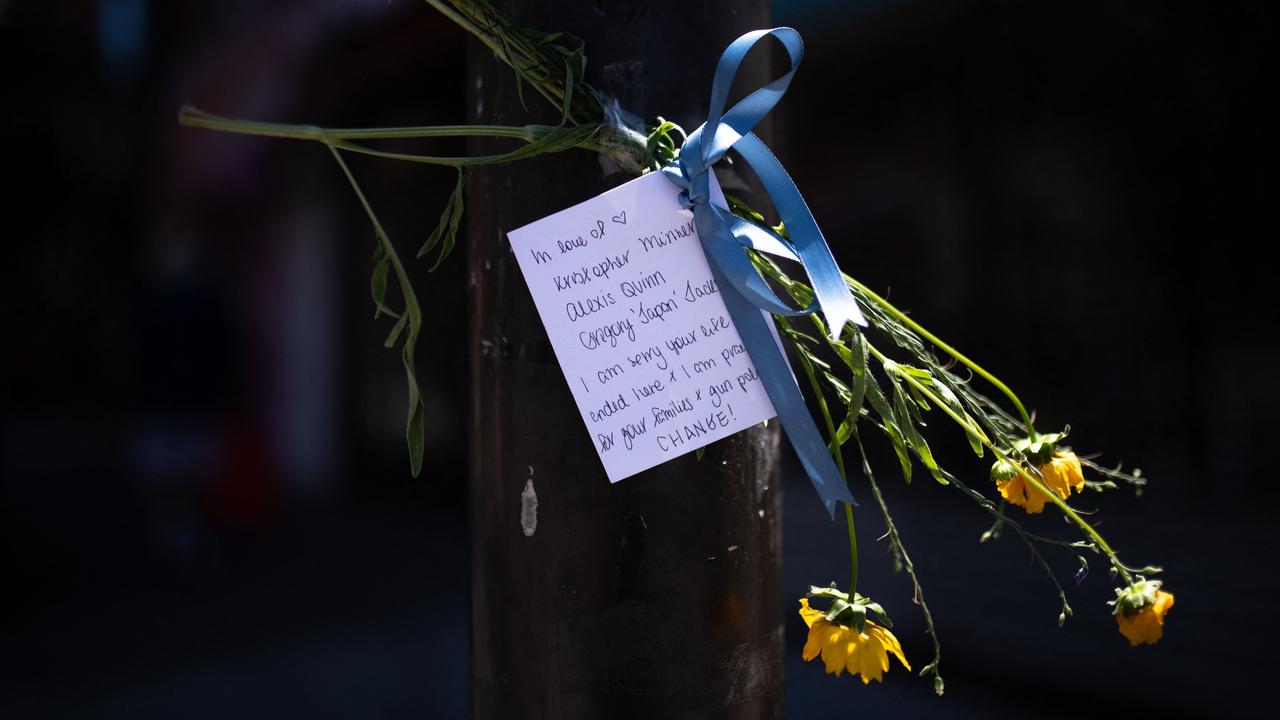 A note and flowers honouring the victims of the mass shooting in Philadelphia are taped to a traffic light post. Picture: Kriston Jae Bethel / AFP