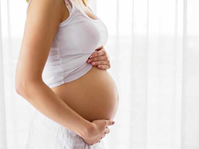 Pregnant woman standing next to window