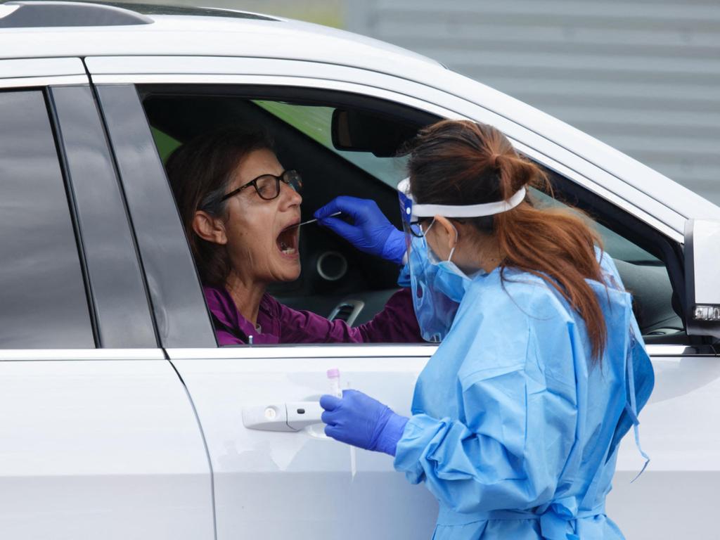 A healthcare worker takes a swab from a patient at a drive-through testing station. Picture: Trevor Collens/AFP