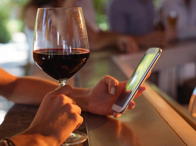 ESCAPE: USA - LaLa Land, Rebecca Andrews.  Hand of woman using mobile phone while having a glass of wine in restaurant . Picture: iStock