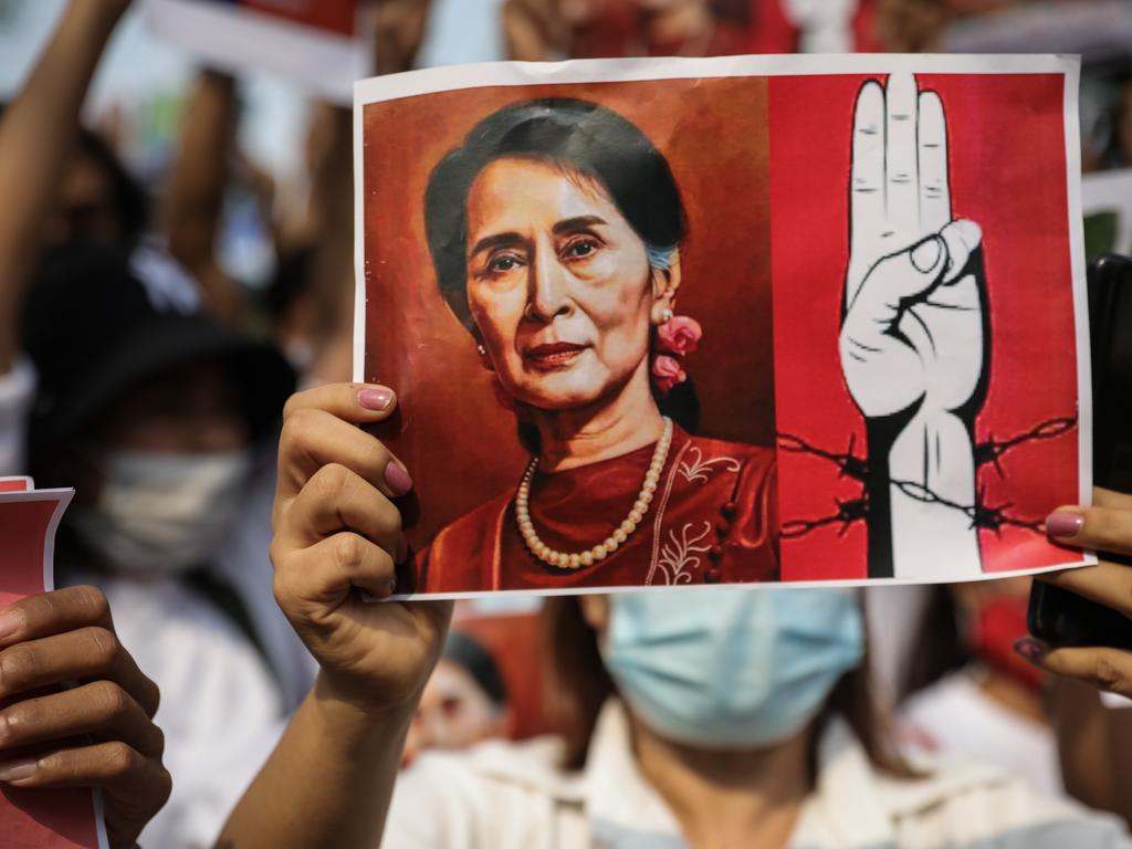 Protesters hold up portraits of Myanmar's de facto leader Aung San Suu Kyi and make three-finger salutes outside the United Nations headquarters in Thailand. Picture: Lauren DeCicca