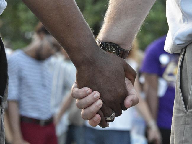 People hold hands at a vigil and march to the Fallen Officer Memorial in Alabama to show unity. Picture: AP