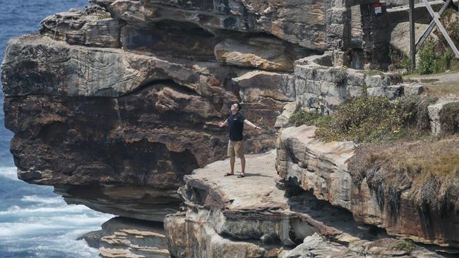 A tourist who has climbed over safety fences in order to get a dangerous selfie at Diamond Bay. Photo: Tim Pascoe