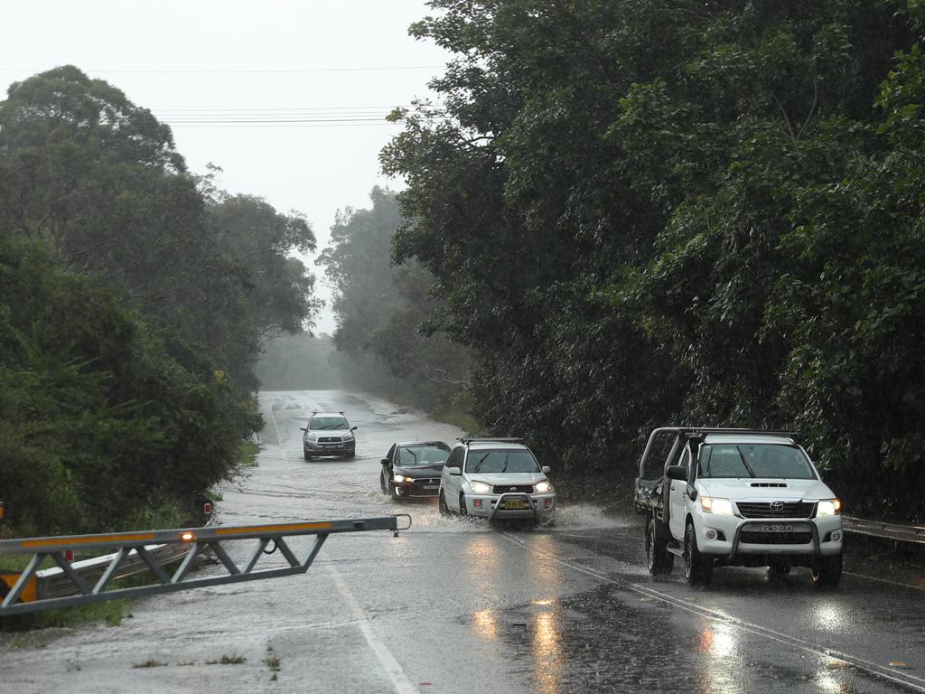 Heavy rain again lashes Sydney , Causing flooding on the Wakehurst Parkway forcing police to close the rd. Police guide the last cars through before shutting the gates . Picture John Grainger