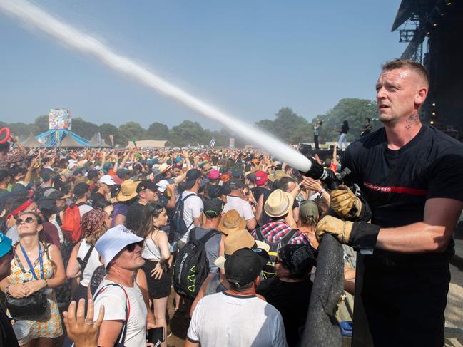 TOPSHOT - Firefighters spray water over festival-goers on the fourth and last day of the 30th edition of the musical festival "Les Vieilles Charrues" in Carhaix-Plouguer, western France, on July 14, 2022. (Photo by FRED TANNEAU / AFP)