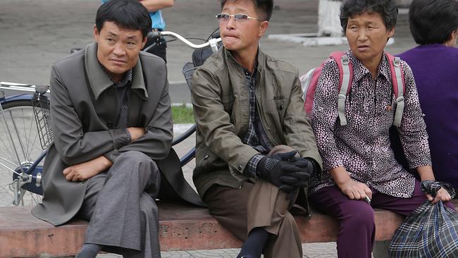 North Korean men and women sit on a stone bench by the road while waiting for a city trolley on Wednesday, Oct. 7, 2015, in Pyongyang, North Korea. (AP Photo/Wong Maye-E)