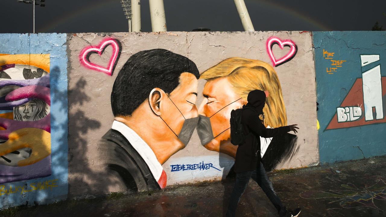 Graffiti depicting China's President Xi Jinping and US President Donald Trump kissing each other with face masks displayed on a wall in Berlin, Germany. Picture: Markus Schreiber/AP