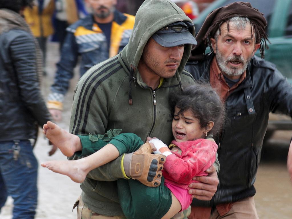 A man carries a girl after an earthquake in the rebel city of Jandaris, Syria.