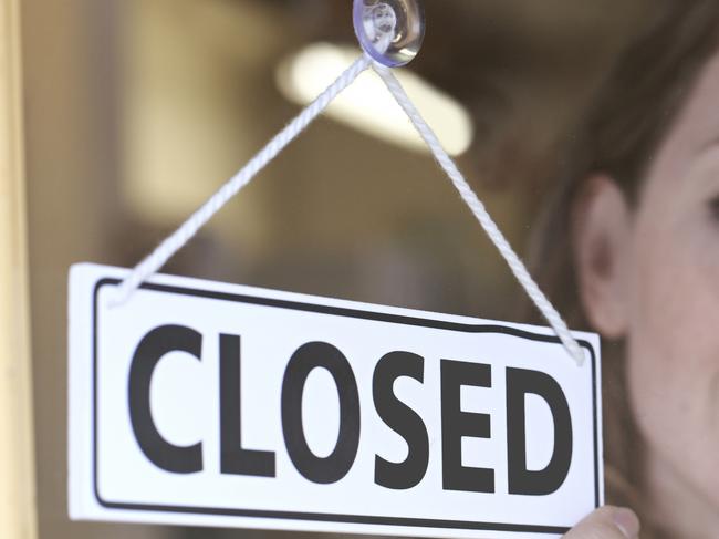 Store Owner Turning Closed Sign In Shop Doorway