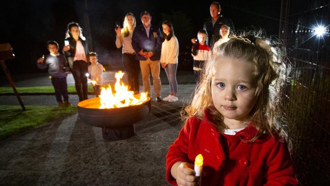 Natalia, 2, holds an old Anzac Day candle with her family having a trial run of the Dawn Service in the driveway. Picture: David Caird