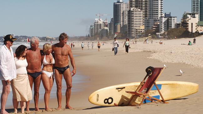 A memorial service for Al Baldwin 'the suntan man' on Surfers Paradise Beach in September 2004, (L-R) Close friends Adam O'Brien, daughter Amber, Karl Bonnett, Sue Bowen and lifeguard Robert Dorrough with Al's Board and Chair. Picture: Paul Riley