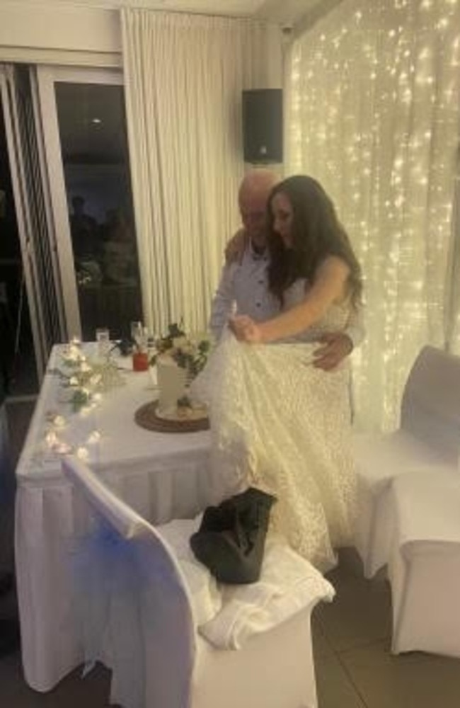 Liz and Adam Costello cutting their wedding cake with the moon boot making an appearance.