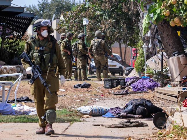 Israeli soldiers stand near the body of a Palestinian militant in Kfar Aza, in the south of Israel. Picture: AFP