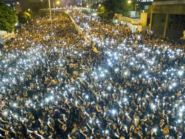 Thousands raise their mobile phones.