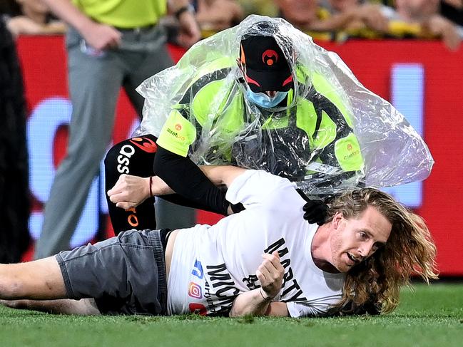 BRISBANE, AUSTRALIA - OCTOBER 24: A pitch invader is caught by security guards during the 2020 AFL Grand Final match between the Richmond Tigers and the Geelong Cats at The Gabba on October 24, 2020 in Brisbane, Australia. (Photo by Bradley Kanaris/AFL Photos/via Getty Images)