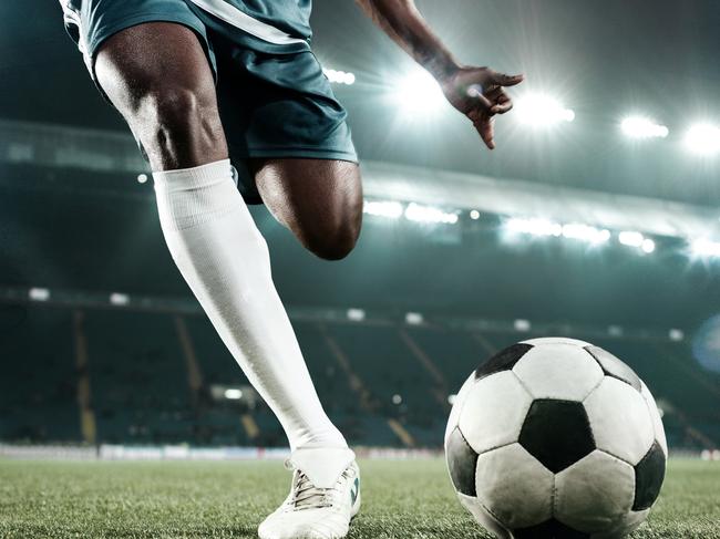 Legs of african soccer player kicking the ball at stadium istock image