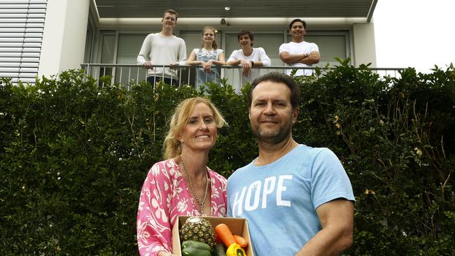 L to R: Diane and Paul Harapin in front of their home with a box of produce while their children Tyler,18, Kaiya, 12, Edyn, 15, and Nathan, 21, watch on from the balcony. Picture: John Appleyard