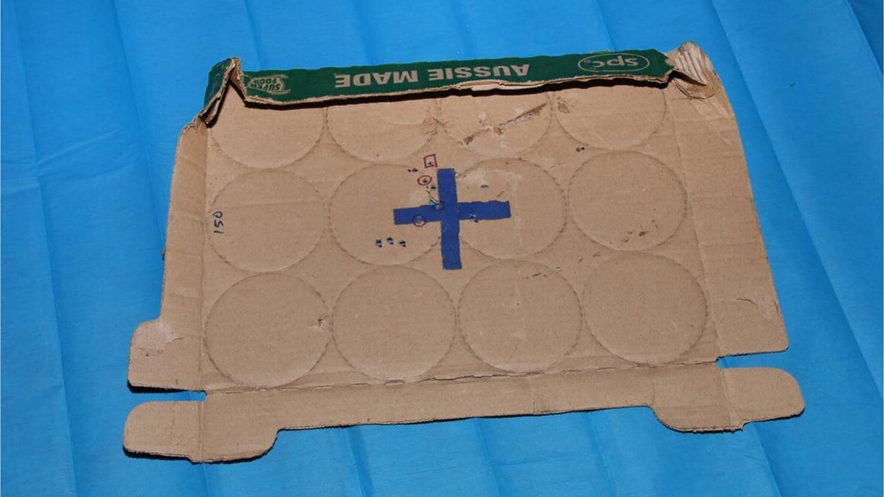 A target made of cardboard with multiple bullet holes through it found at the house.