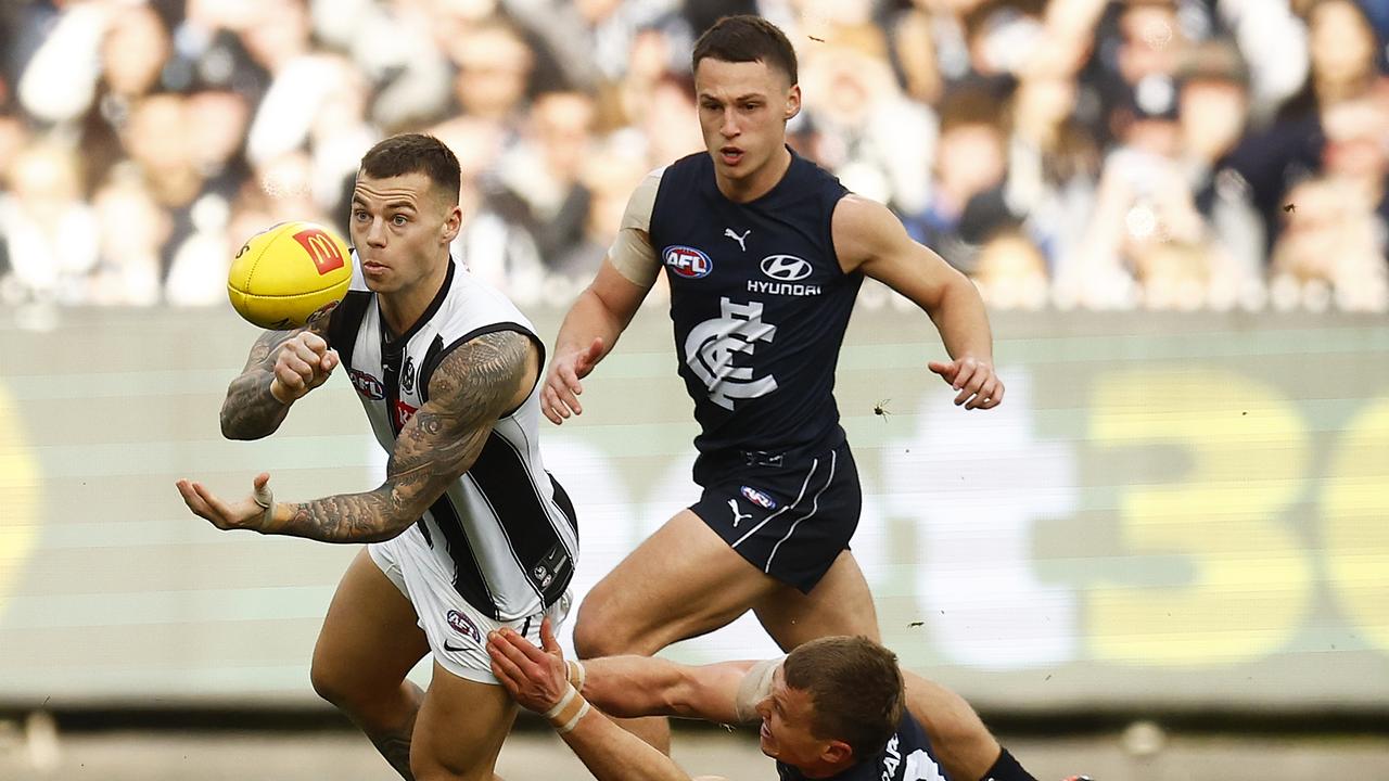 MELBOURNE, AUSTRALIA - AUGUST 21: Jamie Elliott of the Magpies handballs whilst being tackled by Patrick Cripps of the Blues during the round 23 AFL match between the Carlton Blues and the Collingwood Magpies at Melbourne Cricket Ground on August 21, 2022 in Melbourne, Australia. (Photo by Daniel Pockett/Getty Images)