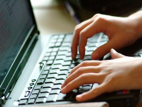 Hands typing on laptop keyboard.