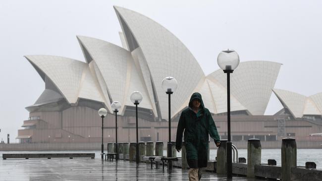 A man braves the rain in front of the Sydney Opera House this morning. Picture: Bianca De Marchi