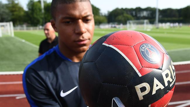 France's forward Kylian Mbappe signs autographs before a training session in Clairefontaine.