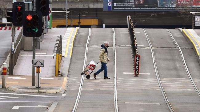 A person crosses an empty street in Melbourne during lockdown. Picture: AFP