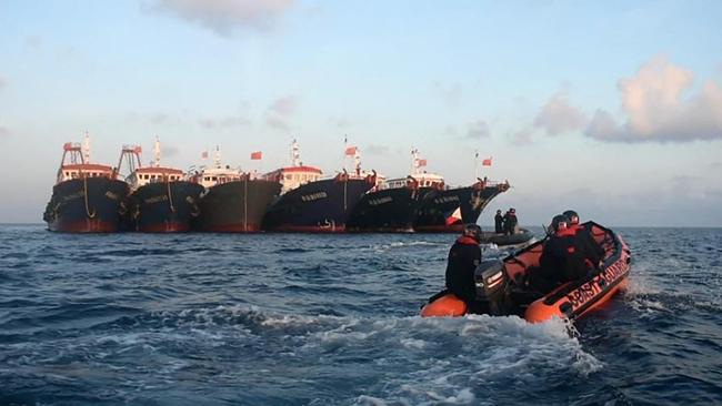 Philippine coast guard personnel aboard rubber boats patrol past Chinese vessels at Whitsun Reef, in the Spratly Islands, two weeks ago. Picture: AFP