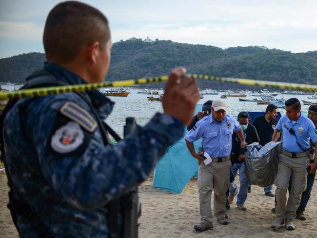 Police officers carry the body of a murdered man from a beach in Acapulco. Picture: Francisco Robles/AFP