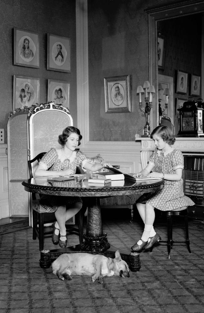 June 22, 1940: Princesses Elizabeth (left) and Margaret study while one of their corgis sleeps at their feet in a drawing room at Windsor Castle, Berkshire. Picture: Lisa Sheridan/Studio Lisa/Getty Images