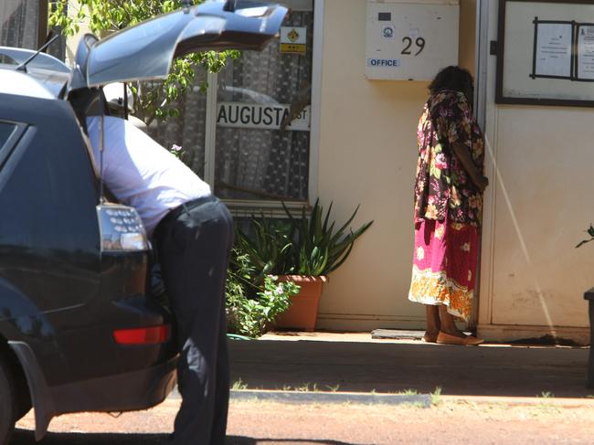 An aboriginal woman looks into Sam's office as Consumer Protection Investigators visit Sam Tomarchio owner of the LA Motel who lends money to aborigines, Laverton, WA. An investigator is getting gear out of there car on the left.