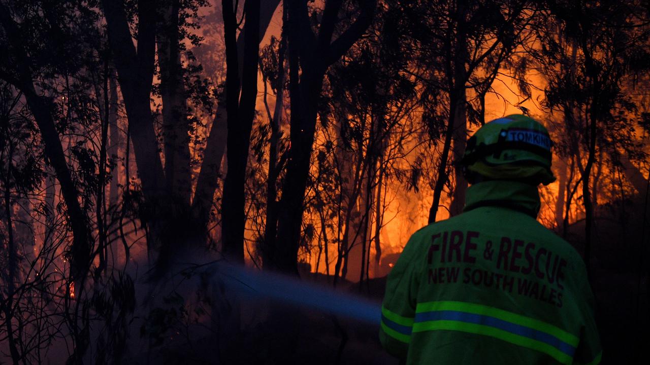 Fire and Rescue NSW firefighters conduct property protection as a bushfire burns close to homes on Railway Parade in Woodford NSW. Picture: AAP Image/Dan Himbrechts