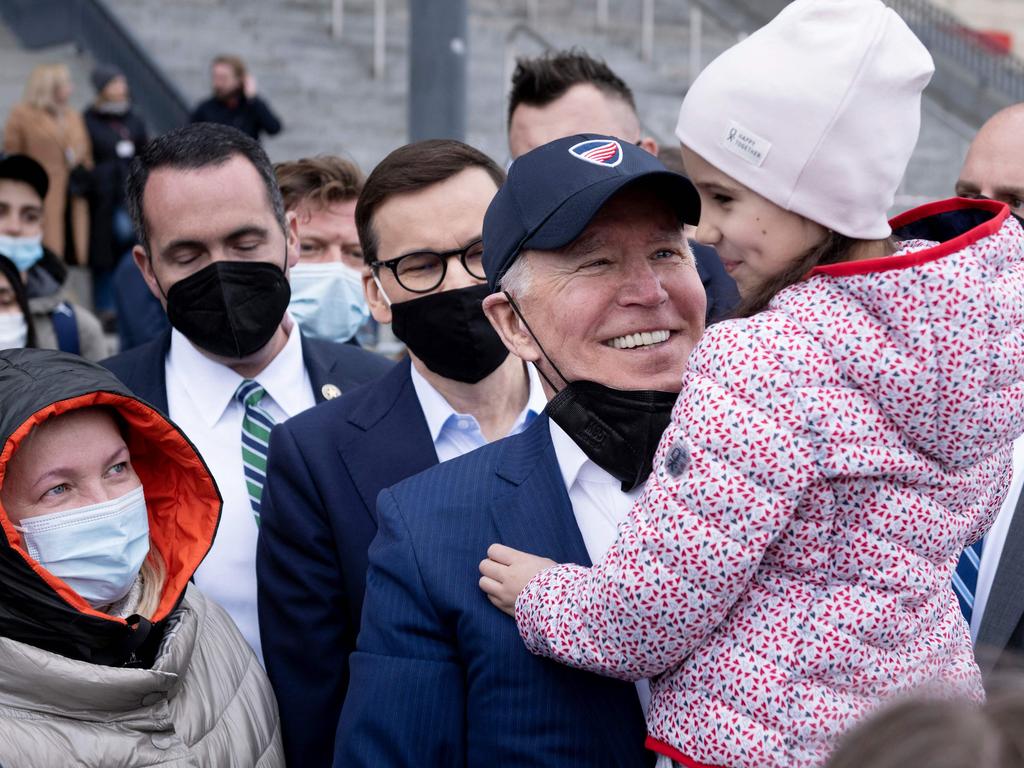 US President Joe Biden holds a girl on his arm as he and Polish Prime Minister Mateusz Morawiecki (centre) meet with Ukrainian refugees at PGE Narodowy Stadium in Warsaw on March 26. Picture: AFP