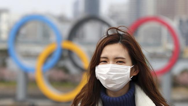 A woman wearing a mask walks near the Olympics' mark in Odaiba, Tokyo on February 22, 2020, amid the outbreak of a new coronavirus in Japan. (The Yomiuri Shimbun via AP Images )