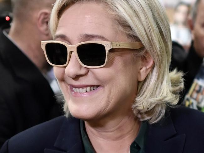 President of the French far-right party and presidential candidate for the 2017 French presidential elections Marine Le Pen (C) tries a pair of glasses during her visit of the 5th edition of the 